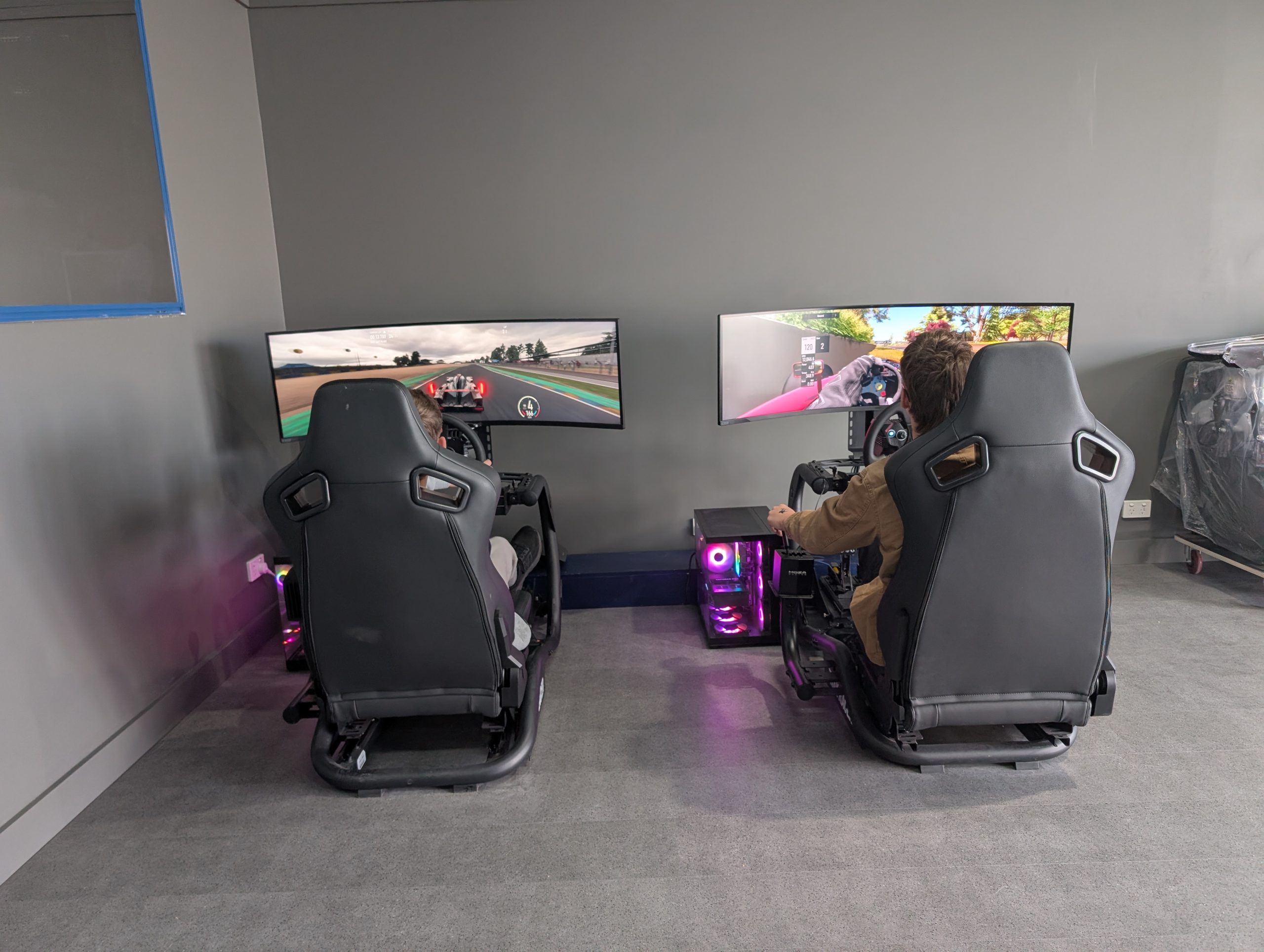 Two drivers on sim racing rigs with wheels, pedals and gear shifters at ESports Collective in Bairnsdale, East Gippsland
